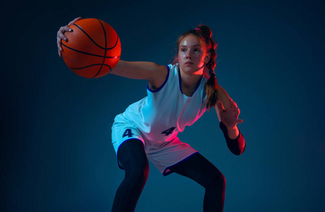 年轻的白人女篮球运动员在蓝色工作室背景霓虹灯