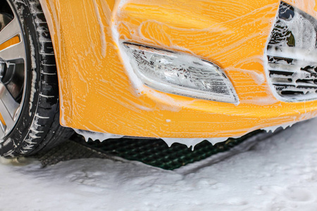 Yellow car front and light washed in self serve carwash. Bumper 