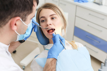 金发女子坐在牙医椅上接受牙医检查