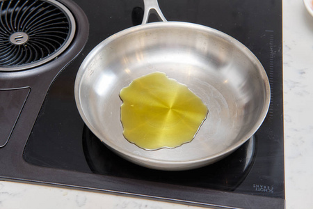 炉子上有橄榄油的煎锅图片