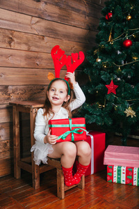 笑容可掬的红鹿角小孩手里拿着圣诞礼物。圣诞节概念。