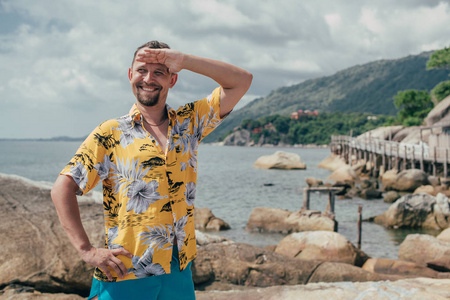 A man stands against a tropical landscape. 