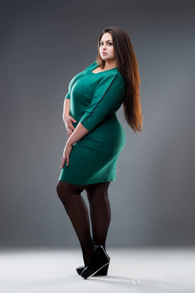 穿绿色连衣裙的大码模特灰色背景下长发的胖女人身材积极
