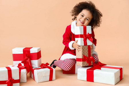 穿着圣诞老人服装，彩色背景上有礼品盒的非洲裔小女孩