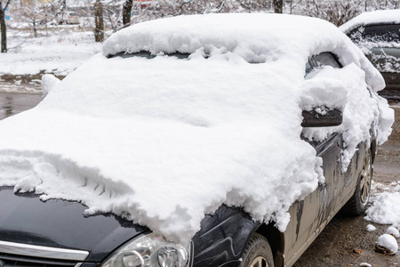 汽车上覆盖着新的白雪，汽车被雪覆盖了一个障碍
