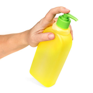 一只雌性的手从黄色的瓶子里倒出洗涤液。孤立在白色背景上。