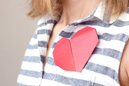 caucasian woman holding origami red paper heart, puts valentine 