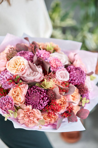 欧洲花店。一束美丽的混合花在女人手中。花店里花匠的工作。送鲜切花。