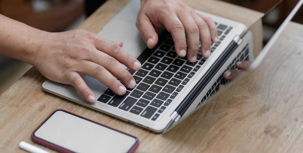 Cropped shot of man working on his project while typing on lapto