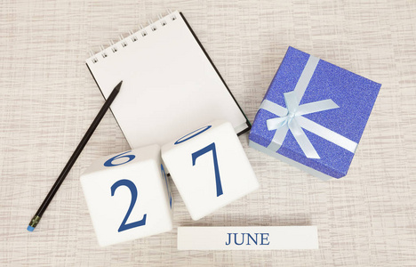 日历上有时尚的蓝色文字和6月27日的数字，还有一个盒子里的礼物。