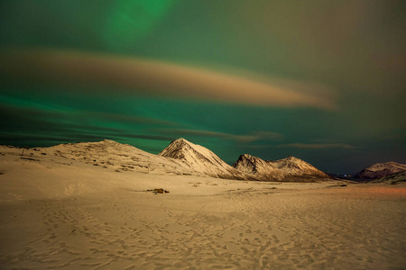 极光，极光和许多云和星星在欧洲北部山脉上空的北极光Tromso，挪威.long快门速度。