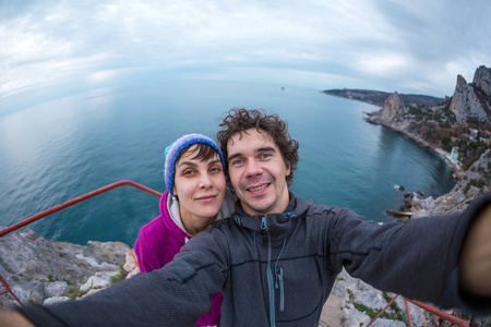 Loving couple takes a selfie on top of a cliff. 