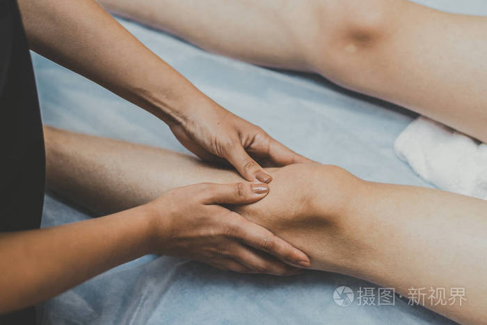 按摩师给年轻人按摩膝盖医生按摩腿部进行治疗