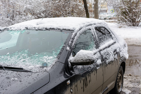 汽车上覆盖着新的白雪，汽车被雪覆盖了一个障碍