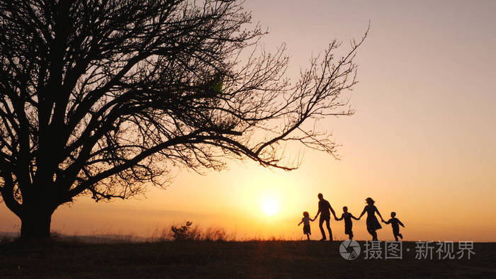 夕阳西下幸福的一家人在草地上散步的剪影
