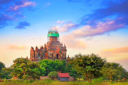 缅甸老巴甘，寺庙上空五彩缤纷的天空被绿色植被包围。