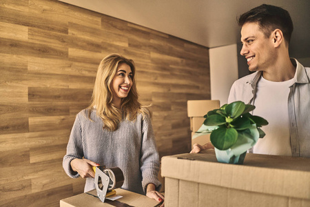 Attractive lovely couple packing a cardboard box with flower to 