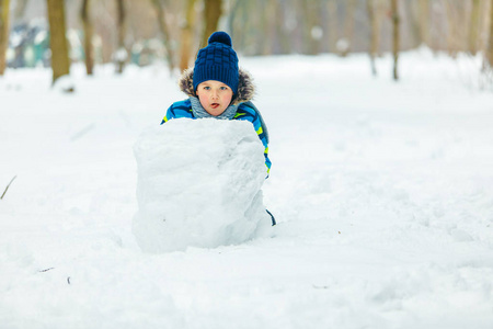 可爱的小男孩在堆雪人。滚大雪球