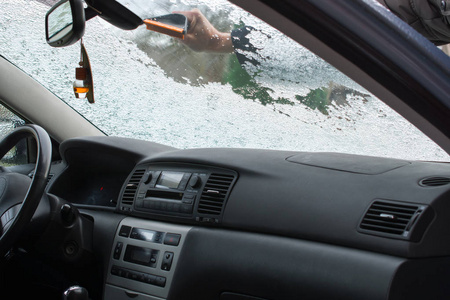 从汽车挡风玻璃上刮冰的人