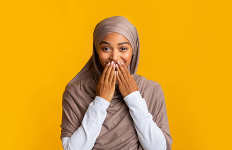 惊讶的黑人穆斯林女孩戴着头巾用手捂住嘴