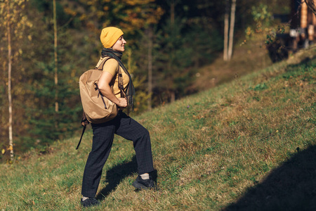 一个背着背包的年轻旅游女孩，秋天在山林中的山上升起。