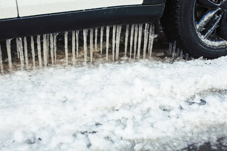 近距离拍摄的车在冰柱下，有很多水和雪，季节性问题的概念