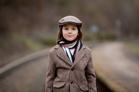 Adorable boy on a railway station, waiting for the train 