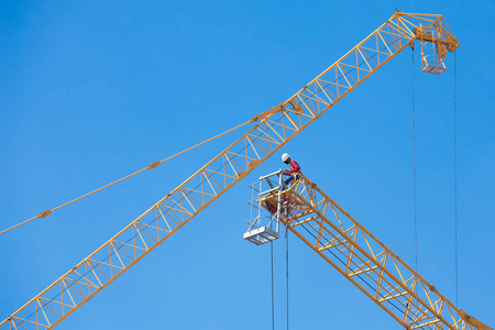 工人们在蓝天上的大型建筑起重机上