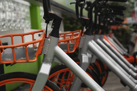 街道交通橙色混合租赁自行车，电子支付形式，用于在城市周围旅行，在租赁网络停车场排队等候骑车人进行自行车旅行。