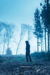在雾蒙蒙的冬季森林里，穿着黑色夹克和裤子的人。