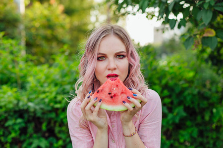 粉红色头发的年轻漂亮女人在吃西瓜