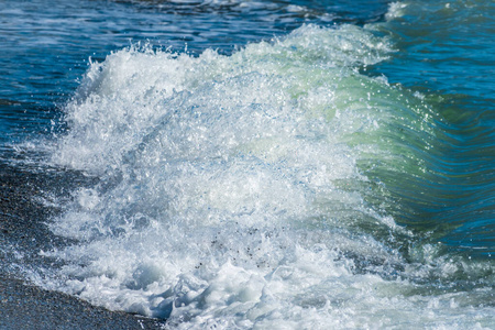 蓝色的海浪在海滩上飞溅着泡沫