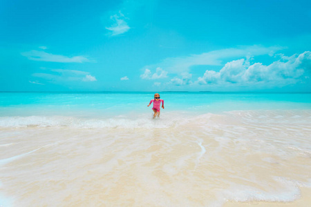 快乐可爱的小女孩在沙滩上玩海浪