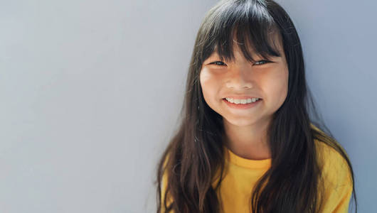 cute little girl smiling on gray background 