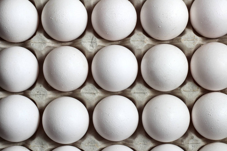 从回收材料中分离出来的鸡蛋托盘，白色背景上有白色的鸡蛋。俯视图