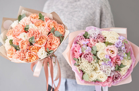 两束美丽的混合花束在女人手中。花店里花匠的工作。送鲜切花。欧洲花店。
