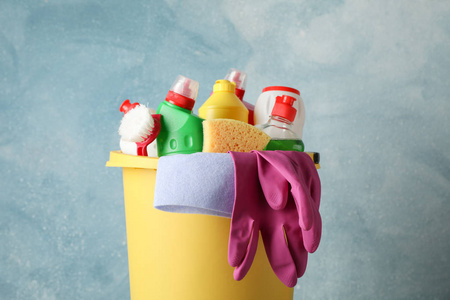 Bucket with detergent and cleaning supplies on blue background, 