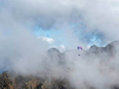 滑翔伞穿越云雾飞过群山图片