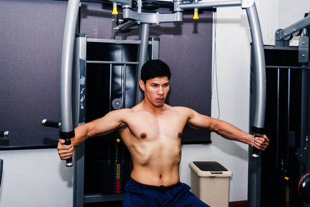 亚洲肌肉男正在健身房举重。