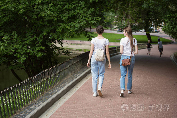 两个女朋友去公园的小巷夏天的学生在公园里散步后视图