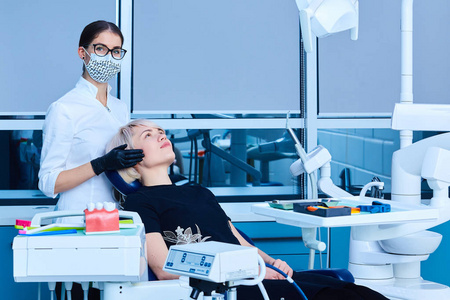 女牙医在牙科诊所为一名妇女检查病人。