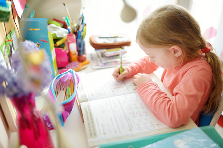 聪明的小女生在家里的桌子上做作业。孩子在学习写作和阅读。