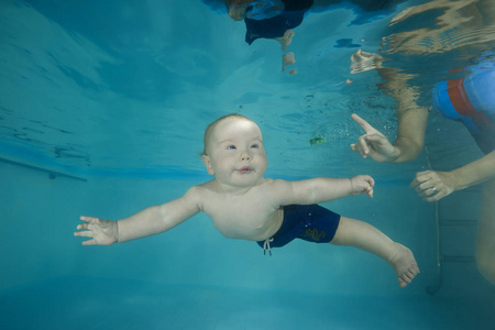 小男孩在游泳池里学着潜水