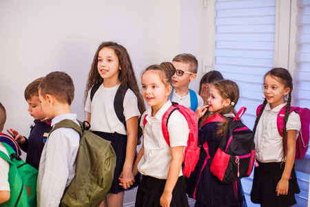 学校走廊上一群背着背包的小学生。回到学校