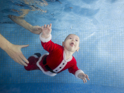 穿着新年礼服的小男孩在游泳池里潜入水下