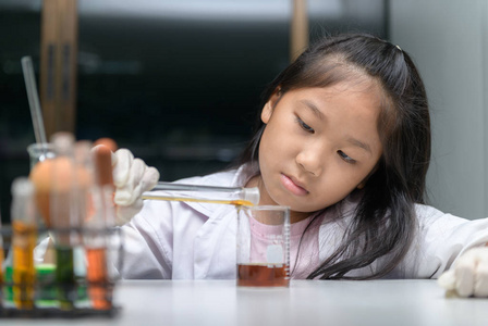 Happy little girl wearing lab coat making experiment 