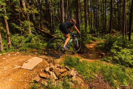 Mountain biking woman riding on bike in summer mountains forest 