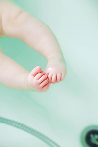 特写照片可爱的新生婴儿脚在洗澡水。