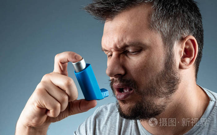 一个手里拿着哮喘吸入器的男人哮喘发作治疗支气管哮喘咳嗽过敏呼吸
