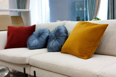 红色蓝色和棕色枕头放在白色沙发上，客厅内部。